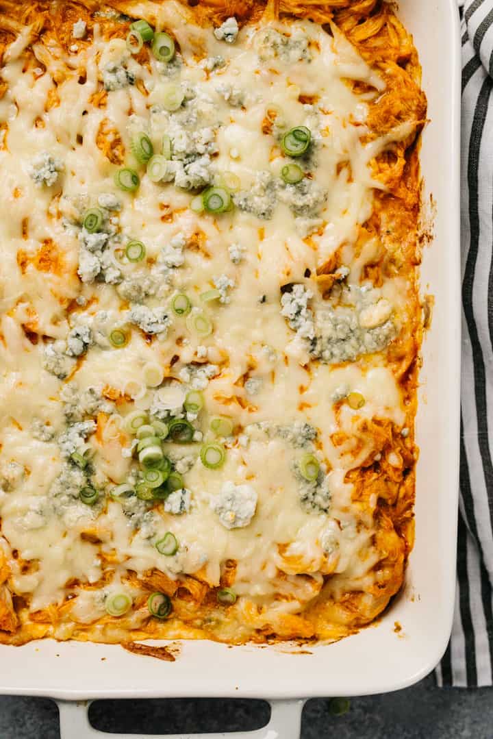 Buffalo chicken dip in a casserole dish with a striped linen napkin on the side.