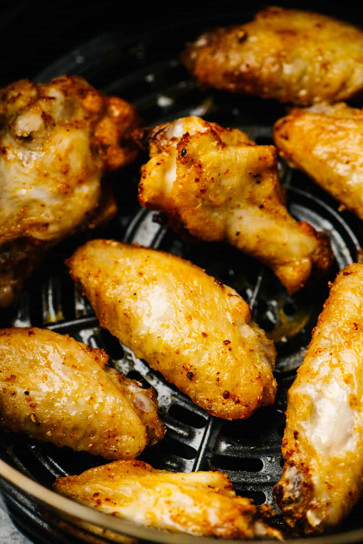 Crispy air fryer chicken wings in a single layer in an air fryer basket.